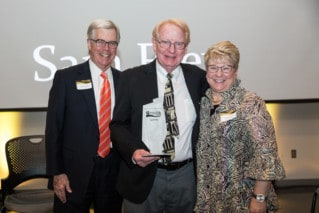Two Men and a woman pose with metal award.