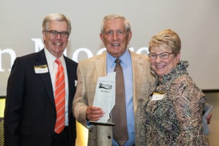 Two Men and a woman pose with metal award.