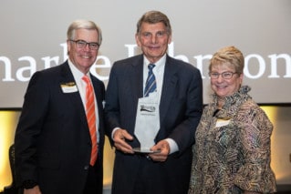 Two Men and a woman pose with metal award.