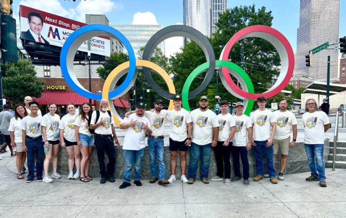 Photo of a large group of WSU Tech Students Standing in front of Olympic Rings
