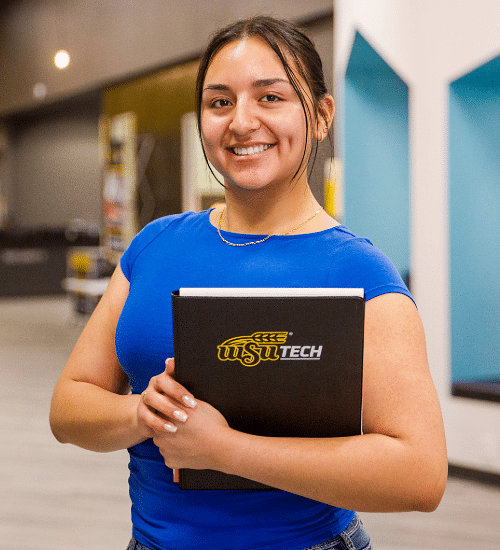 general-student-fa-7 Smiling student holding a WSU Tech notebook inside campus building