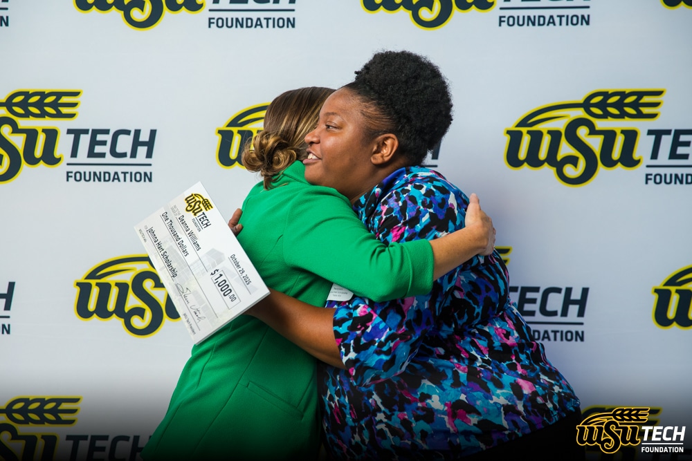 Two women hugging, WSU Tech student holding oversized check