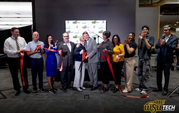 Group of people standing in a line celebrating after cutting a ribbon