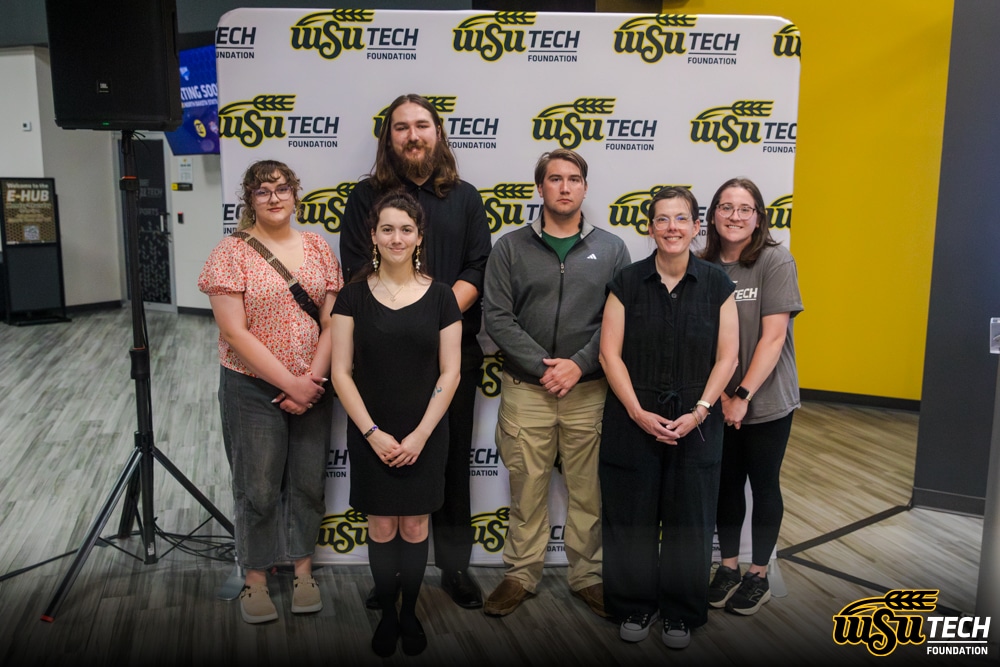 Imagine of 4 female young adults and 2 male young adults posing in front if a WSU Tech step and repeat Backdrop. WSU Tech Foundation logo in bottom corner