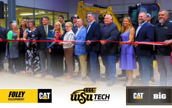 A group of people are gathered for a ribbon cutting ceremony, with a yellow excavator in the background.Foley Equipment logo with CAT logo on a black background.The WSU Tech logo features "WSU" in bold black script with a yellow outline, and "TECH" in bold black sans-serif text underlined in black. A stylized wheat stalk in black and yellow arches over the "WSU" text.The Caterpillar logo, a white "CAT" with a yellow triangle, is on the left. The text "THINK BIG" in white is on the right.