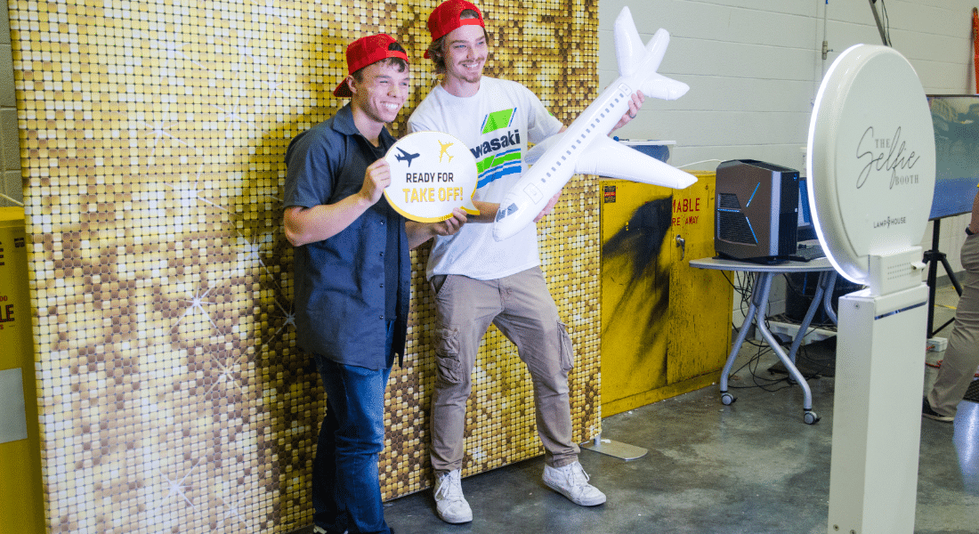 student-resources-hub-student-engagement Students participate in a campus engagement event, posing for a photo with aviation-themed props and a photo booth.